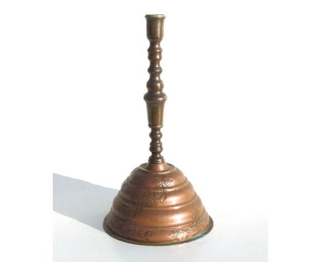 A large Turkish copper candlestick on stepped bell shaped base decorated with flowers and traces of gilding, 38cms high.