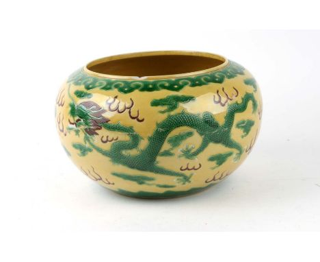 A Chinese famille vert bowl decorated with dragons chasing flaming pearls amongst clouds, on a yellow ground, six character i