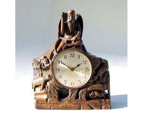 An early 20th century carved oak mantle clock, the case surmounted with a figure of Father Time, the silver dial with Arabic 