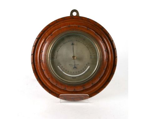 An Edwardian aneroid barometer, the silvered dial signed 'Dollond, London', in an oak case, 30cms diameter.