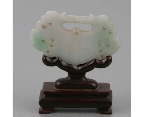 A Chinese carved jade buckle decorated with dragons on a carved wooden stand.