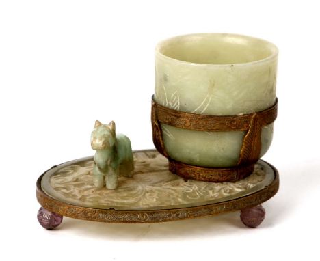 A Chinese gilt metal mounted jade or hardstone cup or brush washer on a pierced stand with three amethyst ball feet, 10cms wi