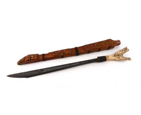 A Dayaka tribe of Borneo Manau sword with carved bone hilt and carved wooden scabbard, 78cms long.