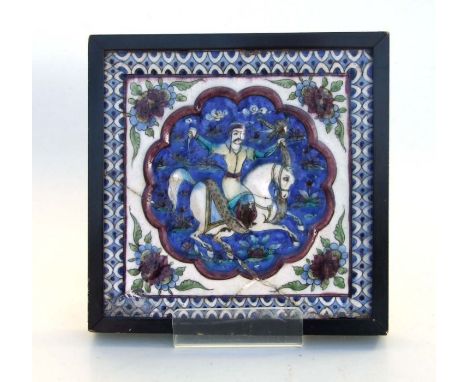 A Persian pottery tile decorated in relief with a figure on horseback fighting a serpent, framed, 21 by 21cms.Condition Repor