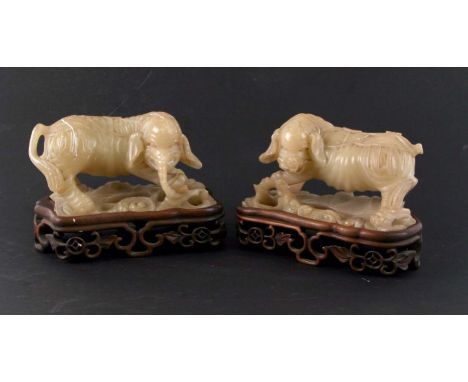 A pair of Chinese soapstone figures depicting stylised elephants on pierced hardwood stands, overall 17cms wide (2). (a/f)Con