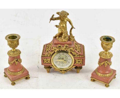 An early 20th century French pink marble and gilt metal mounted clock garniture, the central timepiece surmounted with a cher
