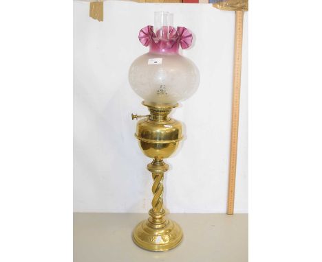 An oil lamp with cranberry tinted frosted glass shade and brass body