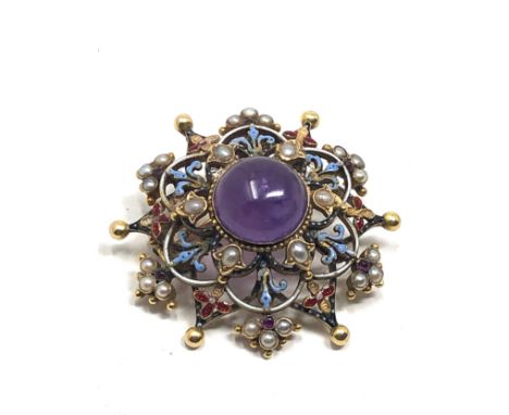 An antique 15 carat gold  with enamel decoration, and set with an amethyst cabochon surrounded by pearl and tiny ruby highlig
