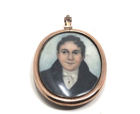 An antique 9 carat gold framed locket pendant;  with a rounded glass holding a finely hand painted sepia portrait miniature o