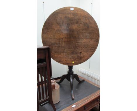 A George III oak circular snap top tripod table, raised on simple cabriole supports