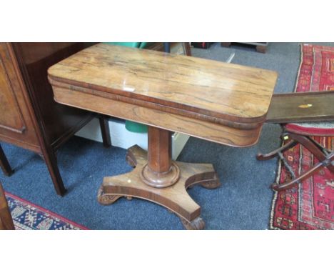 A Regency rosewood card table, the swivel fold over top on octagonal column, concave plateau and scroll carved feet