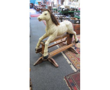 A carved mahogany rocking horse, with horse hair mane and dapple grey finish, raised on a plinth pine trestle, 137 cm (54 in)