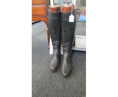 A pair of gentleman's hunting boots, each with wooden trees with brass ring handle