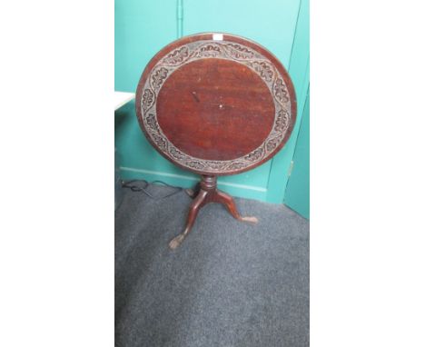 A George III oak tripod table, the circular top with carved oak leaf band on baluster column, three swept legs and hairy paw 