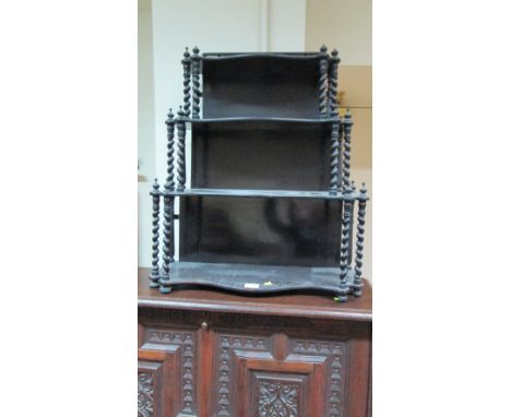 A Victorian ebonised birchwood serpentine three tier whatnot, shelf with open helical column support 