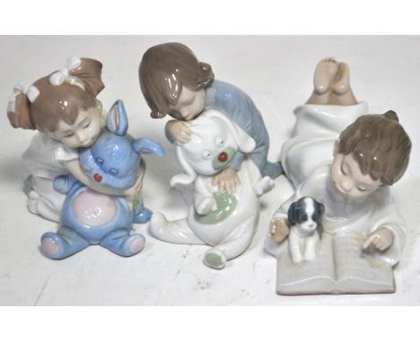 A Nao figurine of a boy reading a book with a dog and Nao figurines of a girls with teddies (3).