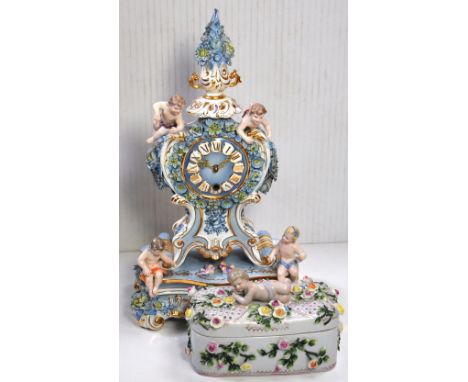 A reproduction Continental mantel clock, cherubic decoration with birds and flowers in relief, dial set with Roman numerals, 