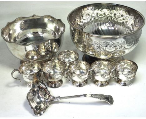 A plated punch bowl with repoussé decoration, six punch cups, a large ladle and a further large plated footed bowl.
