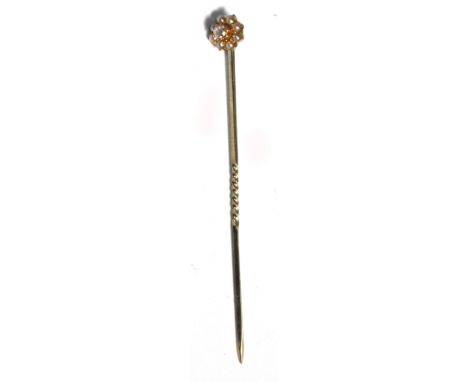 A yellow metal stick pin with central white stone and pearls in a floral setting.