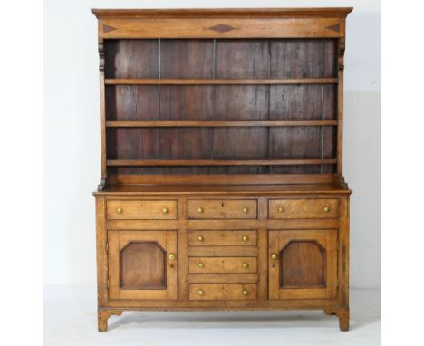 Oak enclosed dresser and plate rack, North Wales, early 19th Century, the boarded rack with a moulded cornice over three shel