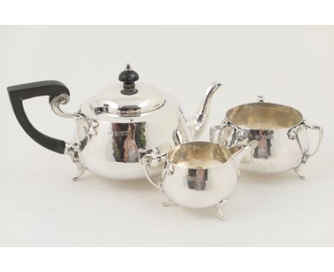 George V silver hand hammered three piece tea service, by Barker Bros., Chester 1923, comprising lidded teapot with domed cov