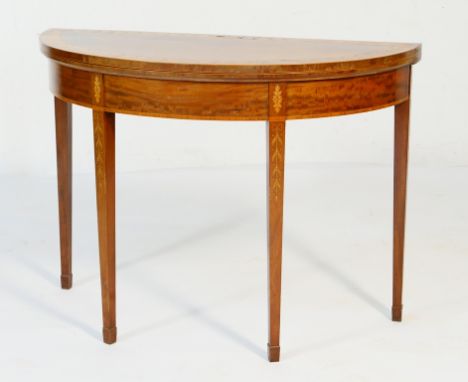 Mahogany and inlaid demi-lune folding card table in the Sheraton style, the top banded with a trail of leaves, folding over t