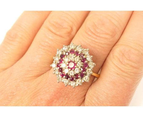 Ruby and diamond cluster ring, coronet target form set with 17 round cut rubies and 24 round brilliants, in a white metal ste