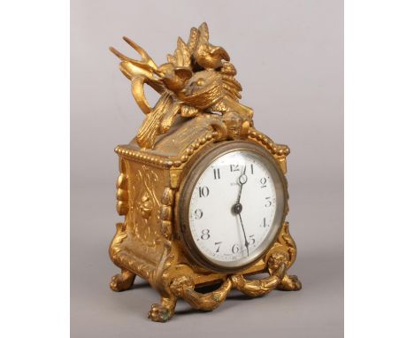 A gilt metal eight day mantel clock, surmounted with nesting birds. 20cm tall.  