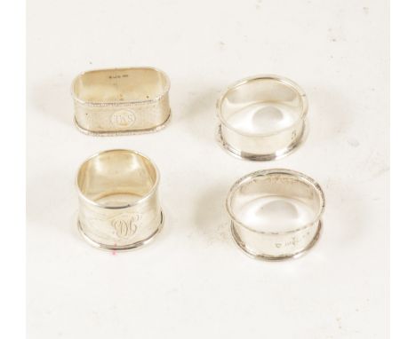 Four Edwardian and later silver napkin rings, some engine-turned, all engraved.