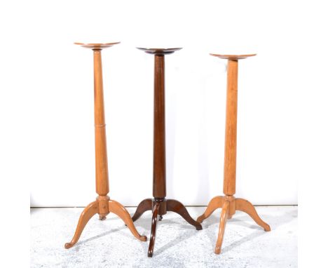 A mahogany torchere, slightly tapering column, tripod legs, height 128cm; and two oak torchere stands. (3)