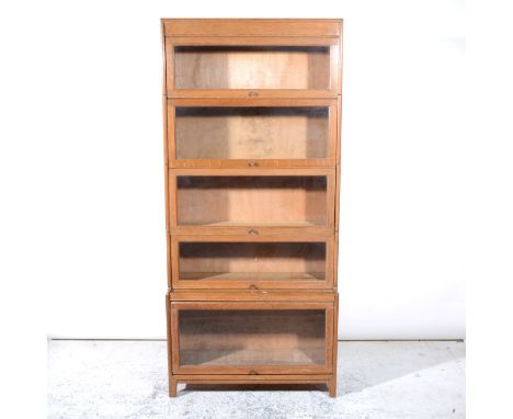 A light oak five height sectional bookcase, glazed panel flaps, width 87cm, height 188cm.