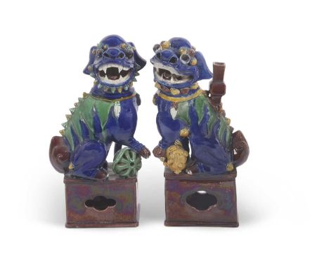 A pair of Chinese dogs of fo or lions on square brown bases with blue Maiolica type glazes, 25cm high