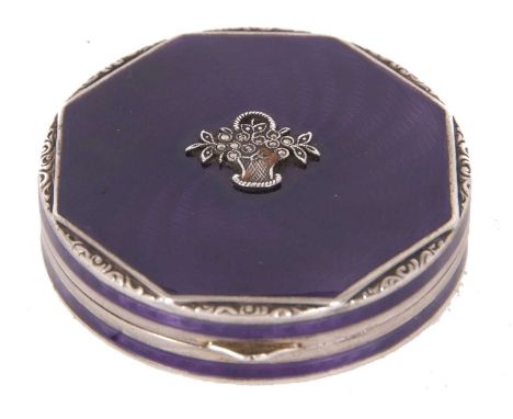 A white metal and enamel compact of octagonal form, the lid decorated with a purple guilloche enamel and applied with a baske