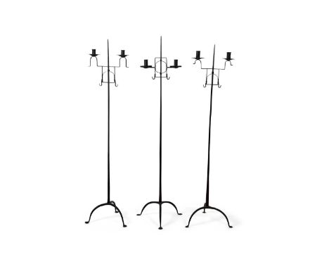 A group of three 18th Century or later wrought iron floor standing adjustable double light candle holders set on tripod bases