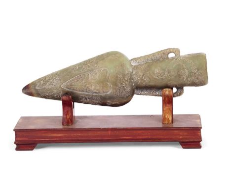 A stone jade type replica of a Chinese harpoon head with carved designs on a wooden display case