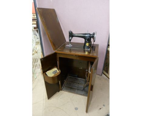 An upright Singer sewing machine, in fitted mahogany cabinet