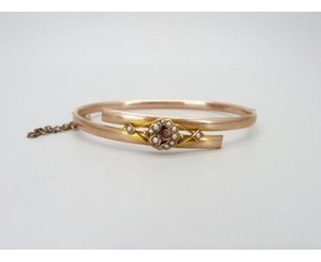 An early 20th Century 9ct rose gold bangle set with seed pearls and a ruby, boxed, 5.4g