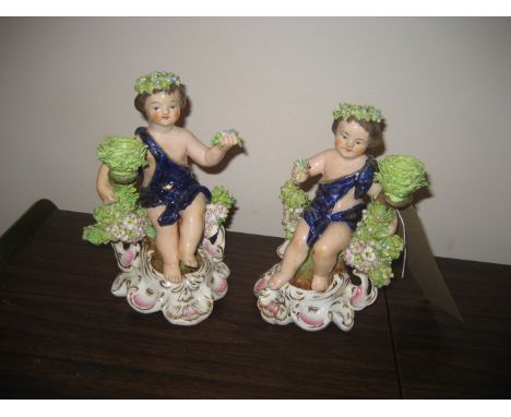 A pair of late 19th century/ early 20th century pottery cherub candle stick holders