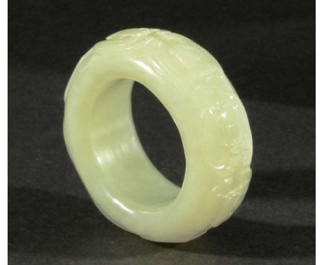 CHINESE PALE CELADON JADE THUMB RING, with carved scrolling decoration, diameter 5cm