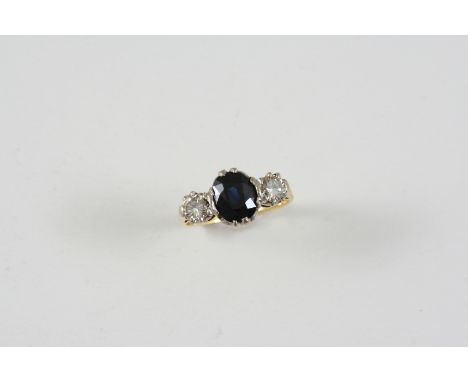 A SAPPHIRE AND DIAMOND THREE STONE RING the oval-shaped sapphire is set with two circular-cut diamonds, in gold. Size J.