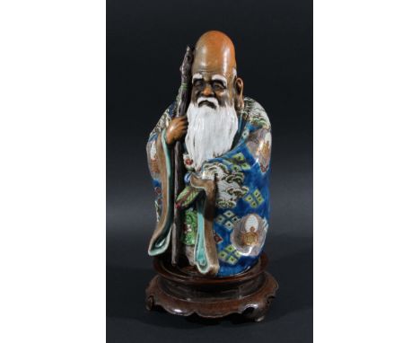 STONEWARE FIGURE OF FUKUROKOJU, standing holding a staff and fan, enamelled wearing a blue and green cloak, height 30cm (with