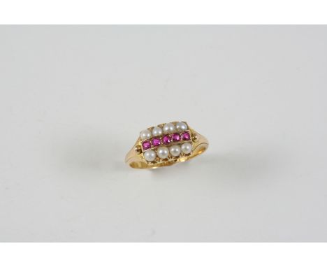 A RUBY AND PEARL RING centred with five circular rubies within a border of half pearls, in 15ct. gold. Size L.