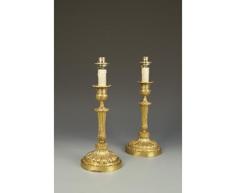 A PAIR OF GILT METAL LOUIS XVI STYLE CANDLESTICK FORM TABLE LAMPS with all over cast floral decoration, on circular bases, la