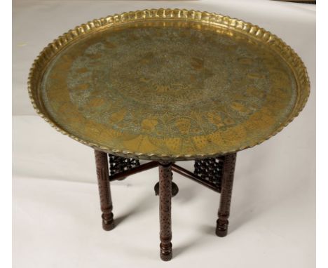 A LARGE MOORISH BRASS/COPPER TRAY-TOP TABLE, the circular top worked with portrait roundels and calligraphy, on a carved fold