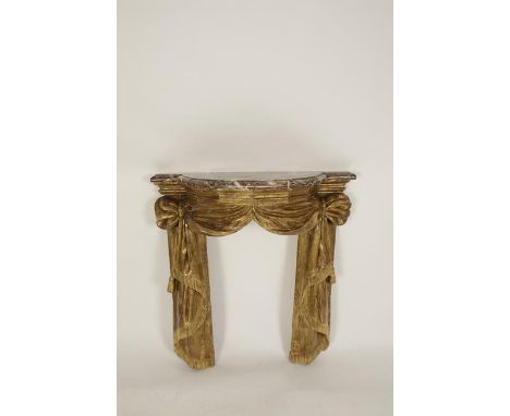 A CONTINENTAL CARVED GILTWOOD AND MARBLE TOPPED CONSOLE TABLE OR FIRE SURROUND in the form of hanging cord tied drapery, 18th