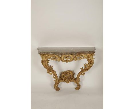 A LOUIS XV CARVED GILTWOOD AND MARBLE MOUNTED CONSOLE TABLE, the serpentine fronted top on a pierced scrolling frieze and twi