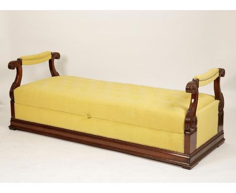 A CHARLES X MAHOGANY OTTOMAN with a broad button upholstered seat with scrolling carved arm-rests to either end, the base sim