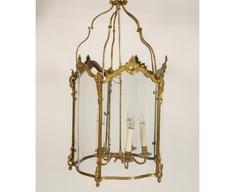 A GILT BRASS HANGING HALL LANTERN with an internal five light chandelier within serpentine fronted five-sided glass shade, 33