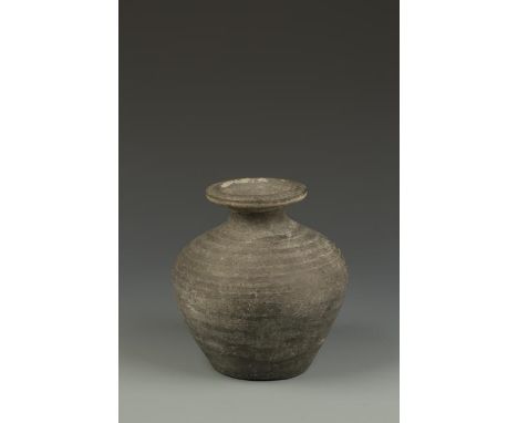 A CHINESE GREY POTTERY OVOID VASE with a flared neck above the broad body, probably Zhou Dynasty, 7.5" high Provenance: The c