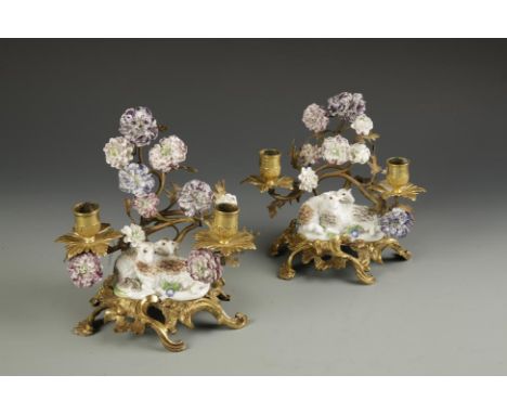 A PAIR OF ORMOLU CANDLEHOLDERS of scrolling rococo form mounted with pairs of sheep and numerous coloured ceramic flowers, ea